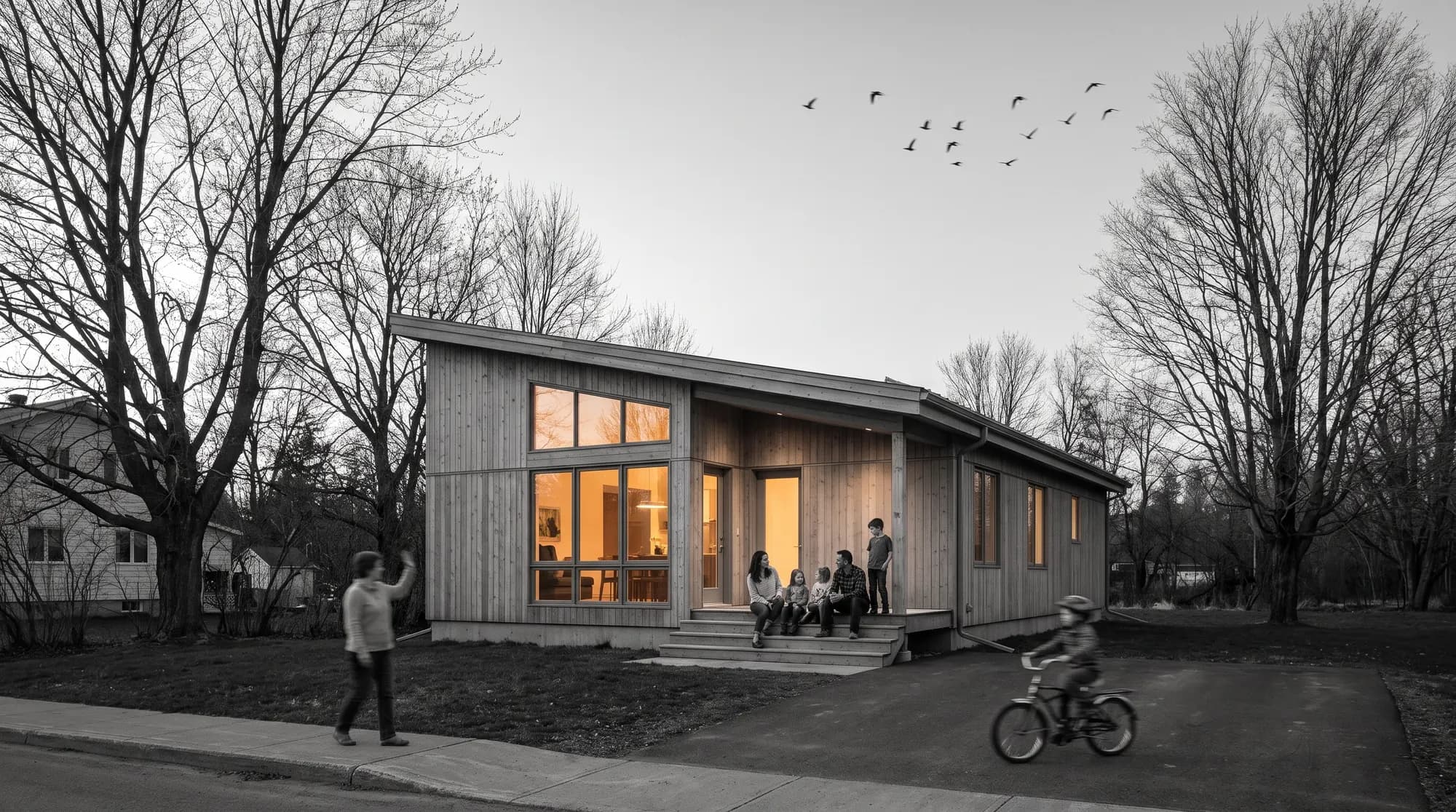 A family on the porch of a finished timber home, a neighbour waving, a child on a bike